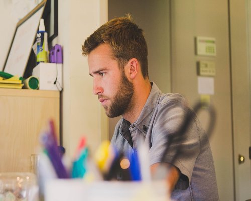 Person standing up stretching arms slightly next to office desk